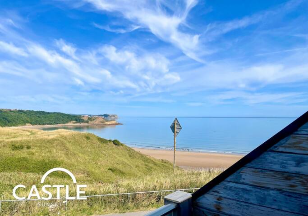 View from Castle Sunset across the dunes to the sandy beach and calm sea at Cayton Bay