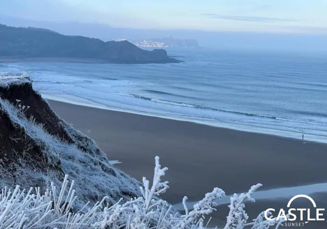 Frosty winter morning on the clifftop above Cayton Bay, looking along the empty beach towards the lights of Scarborough