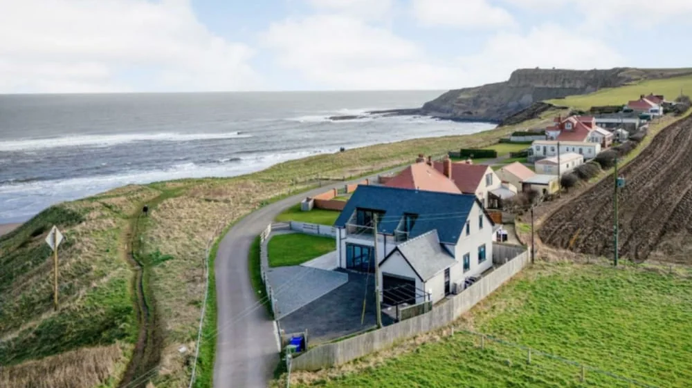 Castle Sunset on the Beach from the air: the house on the clifftop above Cayton Bay, with the beach and headland beyond