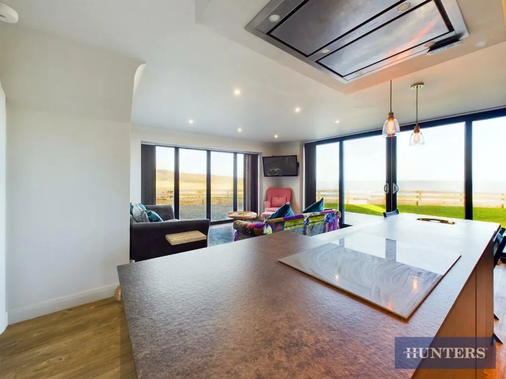 The kitchen island and dining table, with the wall of glass and the sea beyond